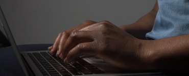 Close up of hands typing on a laptop keyboard.