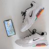 An overhead view of a pair of Nike sneakers set aside an iphone displaying a map on its screen