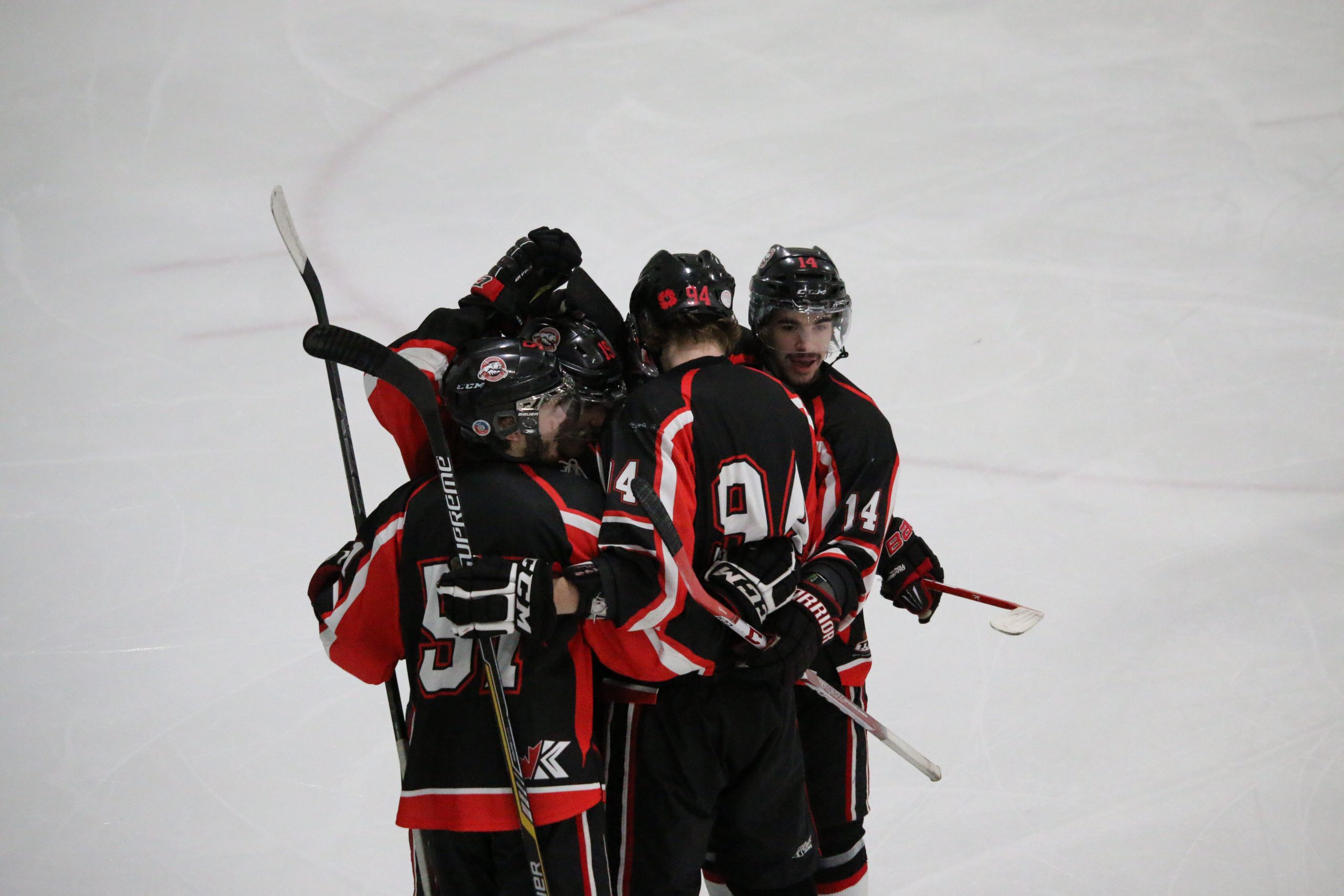 group of hockey players with their sticks in the air huddling together on the ice