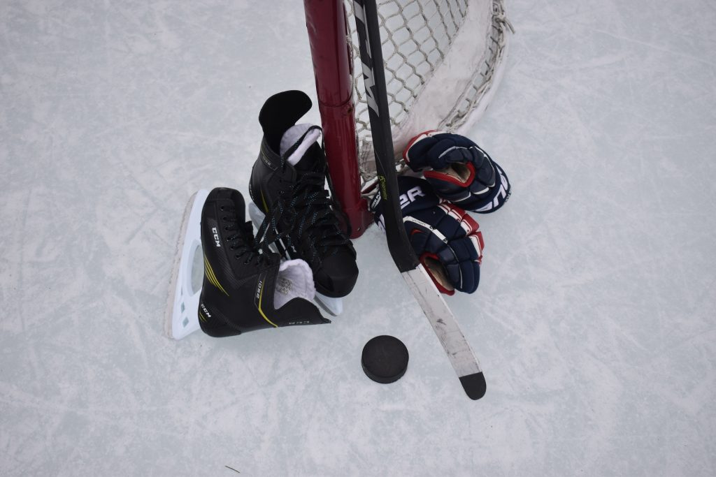 Hockey equipment laid out beside a hockey net on rink