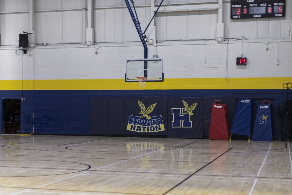 Wide shot of the Humber basketball court with the Hawks Nation mats against the wall